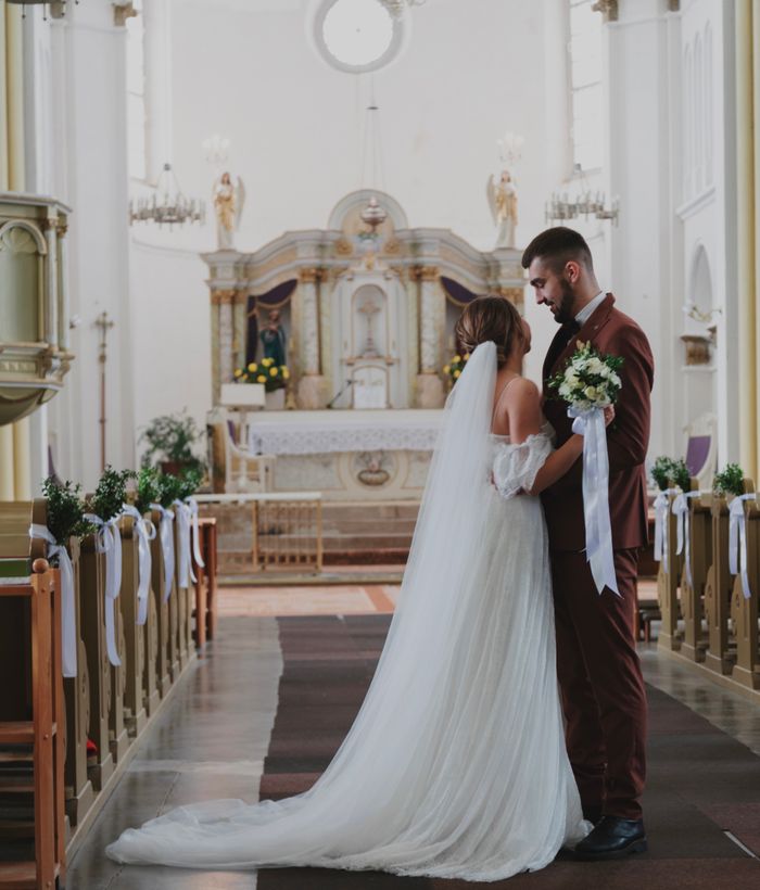 A lovely wedding ceremony inside a grand cathedral, with the bride and groom embracing.